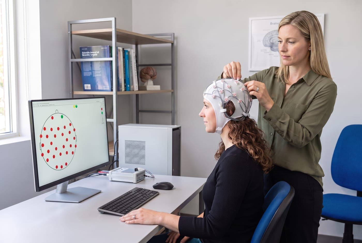 Behandelaar plaatst een EEG-meetkap bij een cliënt tijdens een braintraining bij Neo Clinics